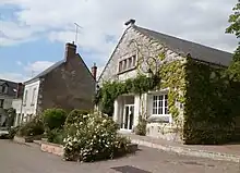 Photographie en couleurs d'un bâtiment public dont le pignon, ouvert par une large porte, est partiellement couvert de végétation.