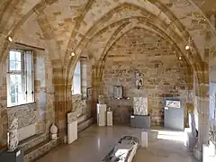 Salle voûtée en pierre avec des sculptures exposées.