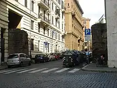 Photographie en couleurs d'une rue passant par la brèche d'une muraille