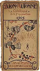 Surface cartonnée beige rectangulaire orientée en hauteur. Imprimés dessus, des caractères et dessins, noirs et rouges