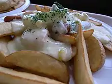 Plat de frites, saucisses, fromage fondu et fines herbes