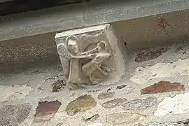 Un ange tenant avec la main droite un animal (un porc ?) par l'oreille et de la main gauche un anneau.