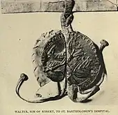 Photographie sombre d'un sceau appendu où on aperçoit des motifs à chevrons