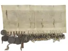 Photographie d'un document manuscrit en parchemin auquel plusieurs sceaux sont attachés.