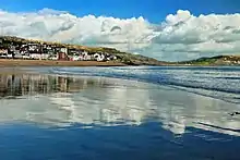 photo. Vue générale du port de Lyme Regis, au second plan, se reflétant dans la mer à marée descendante