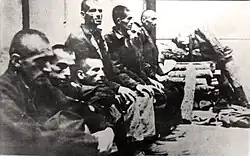 Un groupe de prisonniers, le cheveu coupé ras.