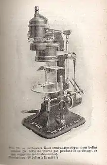 Gravure représentant un haut appareil dont la forme peut faire penser à un microscope ; la base en fonte était vissée au sol ; la boîte était placée à l’endroit où on déposerait l’objet à examiner au microscope ; le mécanisme est fait de tiges de fer, de courroie, de ressort.