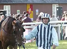 Homme vu de face tenant son cheval par la bride