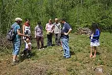 Des personnes forment un cercle autour d'un guide qui montre une plante rare.