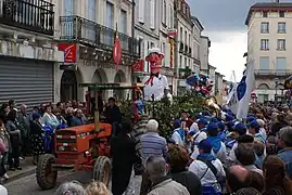 Le mannequin Bufador est remorqué par un tracteur dans une rue de Nontron, au milieu d'une foule de spectateurs.