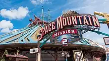 Panneau sur lequel est écrit « Space Mountain Mission 2 » devant un bâtiment bleu et doré.