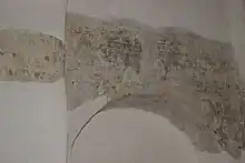 Arc en pierre replâtré de frais au-dessus duquel on aperçoit des traces de peinture ancienne.