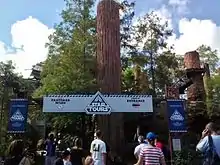 Personnes devant un panneau avec une forêt derrière.