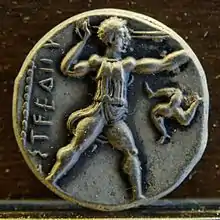 Frondeur debout à droite, triskèle dans le champ à droite. Revers d'un statère d'argent d'Aspendos, Pamphylie.