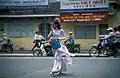 Étudiante traversant la rue, vêtue d'un áo dài (Hô Chi Minh-Ville, 2002).