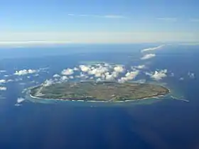 Vue aérienne couleur d'une île, dans une étendue d'eau bleue.
