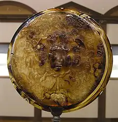 coupe ronde en pierre sculptée représentant la tête de Méduse.