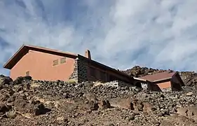 Bâtiment rosâtre dans un paysage rocheux.