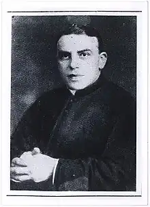 Photo noir et blanc d'une personne assise, mains croisées.