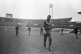 Plusieurs personnes en survêtement marchant de face sur une pelouse.