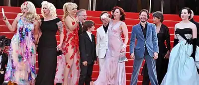 Environ 12 personnes sur tapis rouge, souriantes, riantes, en mouvement, regardant dans tous les sens.