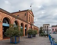Photo de la mairie de L'Isle-en-Dodon : un bâtiment en briques avec des arcades et un étage au niveau de l'entrée. Le drapeau français et celui de l'Union européenne flottent au balcon au dessus de l'entrée.