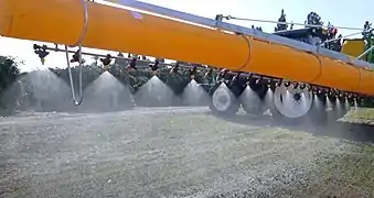 Rampe de pulvérisation, ses buses et son manchon réducteur de dérive sur un pulvérisateur porté sur un tracteur.