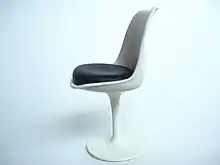 Miniature de la chaise Tulipe sur un fond blanc. Celle-ci se compose d'un pied corolle blanc, d'une coque blanche incurvée. L'assise est noire.
