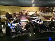 Photo de deux voitures bleues et blanches exposées dans un musée