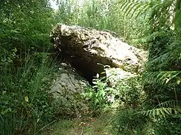 Un bloc de pierre brute posé hoizontalement sur trois autres blocs de pierre brute verticaux.