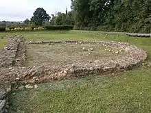 Photographie en couleurs de la base d'un mur semi-circulaire.