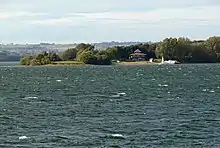 photo d'une maison au bord d'un lac, avec deux bateaux accostés sur la plage.
