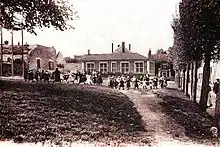 Vue d'une école et des enfants dans la cour sur une carte postale ancienne sépia.