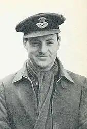 Photo en plan américain de Whitney Straight, portant l'uniforme de la Royal Air Force, une écharpe et une casquette.