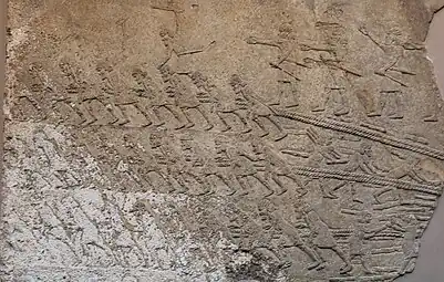 Des ouvriers tirent des cordes tractant une statue de taureau ailé, bas-relief du Palais sud-ouest de Ninive (début VIIe siècle av. J.-C.). British Museum.