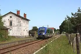 Un TER de type X 73500 passe sans arrêt devant l'ancien bâtiment voyageurs de la gare.