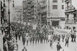 Une foule d'afro-américains en costume avec un chapeau sur la tête défile derrière une banderole.
