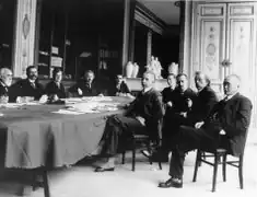 photo en intérieur d'un groupe d'hommes en costume assis autour d'une table.