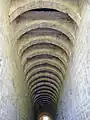 Canal du bâtiment des latrines dont les arcs délimitent l'ouverture des 60&nbsp;sièges des moines à l'étage.