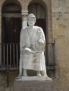 Statue en pierre claire représentant un homme assis.