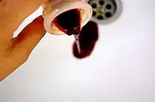 Une coupe menstruelle contenant du sang est vidée dans un lavabo