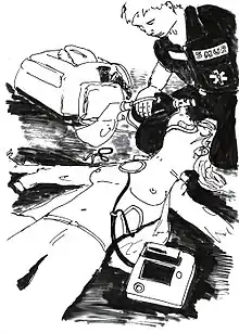 Vue de l'opérateur du défibrillateur : Un secouriste est à genoux à la tête de la victime et lui administre de l'oxygène. Si la tête de la victime est entre ses genoux, elle n'est pas serrée. Les électrodes de défibrillation sont collées.