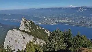 Photographie en couleurs d'une ville a l'arrière-plan d'un grand lac ; éperon rocheux au premier plan.