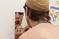 Drag queen se maquillant dans un miroir, en utilisant du rouge à lèvres