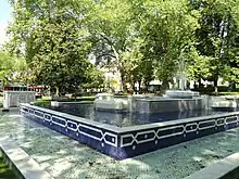 Photographie en couleurs d'une fontaine dans un espace vert public.