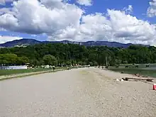Vue en couleurs sur une plage en bordure d'une étendue d'eau.